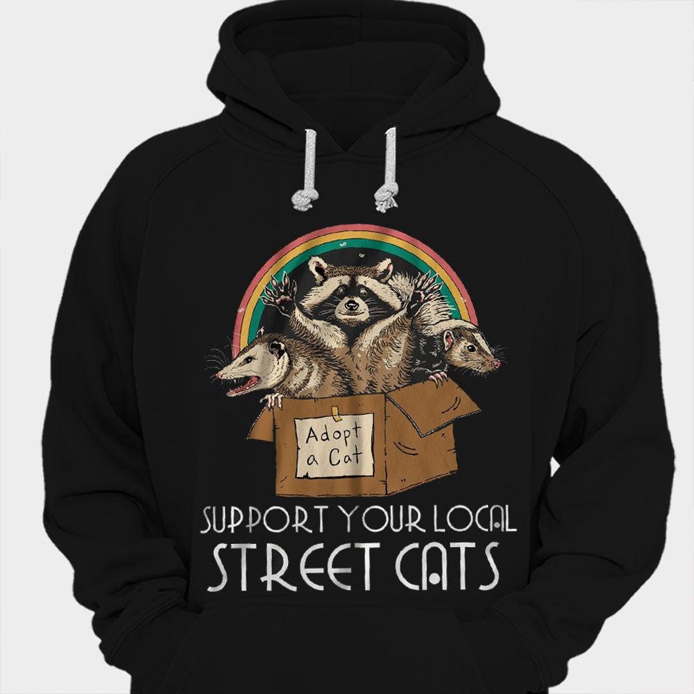 Camisetas de mapache arcoíris con el logo de "Apoya a tus gatos callejeros locales"